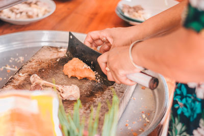 Cropped hands of woman cutting raw meat