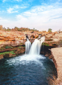 Scenic view of waterfall against sky