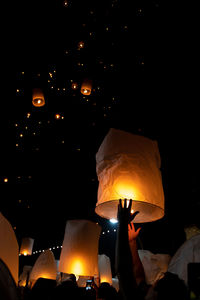 People holding illuminated lantern at night