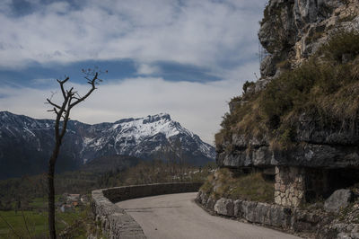 Road amidst trees and mountains against sky