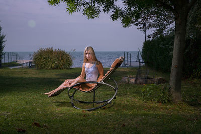 Portrait of woman sitting on seat against sky