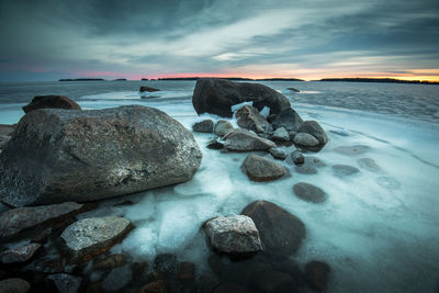 Rocks in sea during sunset