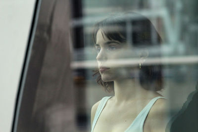 Portrait of young woman looking through window