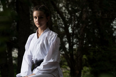 Young woman standing against trees