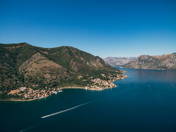 Scenic view of lake and mountains against clear blue sky