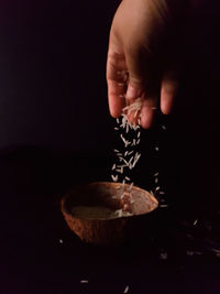 Close-up of hand holding ice cream against black background