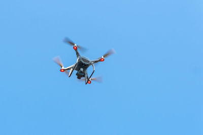 Low angle view of airplane flying against clear blue sky