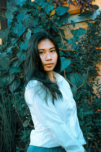 Portrait of beautiful young woman standing against bright sun