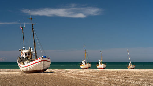 Sailboats moored on sea against sky