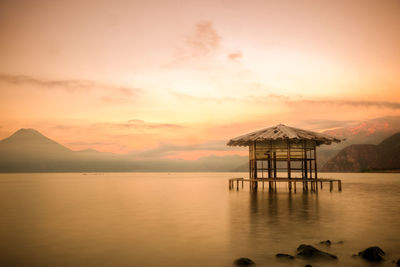 Built structure by sea against sky during sunset