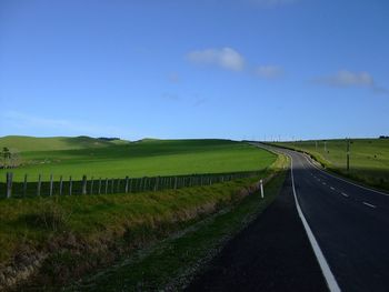 Road amidst field against clear sky