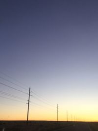 Low angle view of silhouette electricity pylon against clear sky