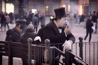 People sitting by railing in city