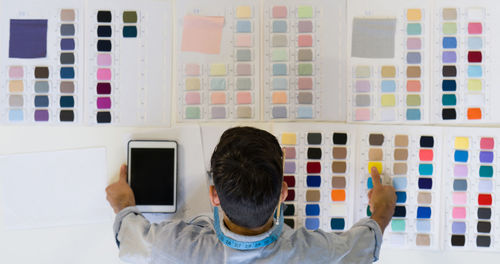 Rear view of man standing against multi colored wall at home
