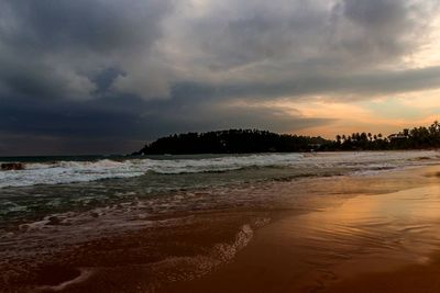 Scenic view of beach against dramatic sky