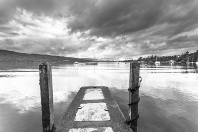 Wooden posts on river against sky