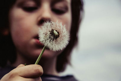 Close-up of hand holding dandelion