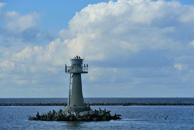 Lighthouse by sea against sky