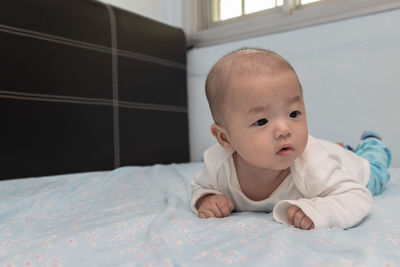 Portrait of cute baby lying on bed at home