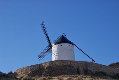 Low angle view of traditional windmill against clear blue sky