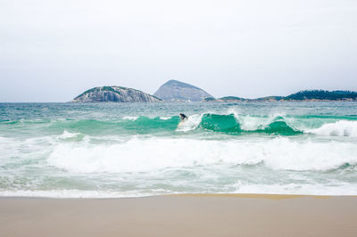 Surfer surfing waves against clear sky