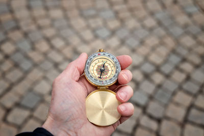 Close-up of hand holding navigational compass on footpath