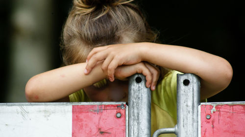 Close-up of sad girl by fence