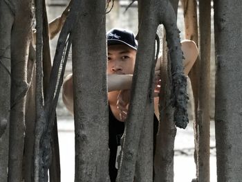 Portrait of boy holding mobile phone by tree trunk