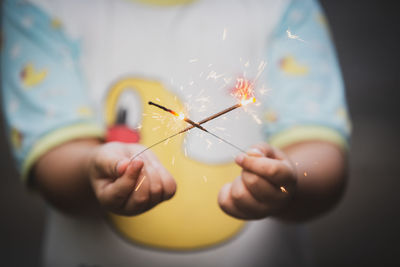 Close-up midsection of boy holding sparklers 