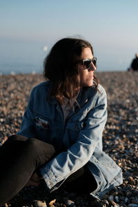 Woman wearing sunglasses sitting on land against sky