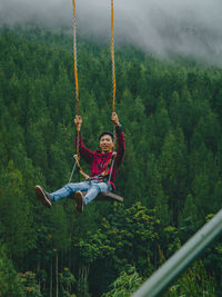 Low angle view of woman swinging in playground