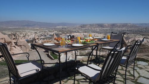 Chairs and table on landscape against clear sky