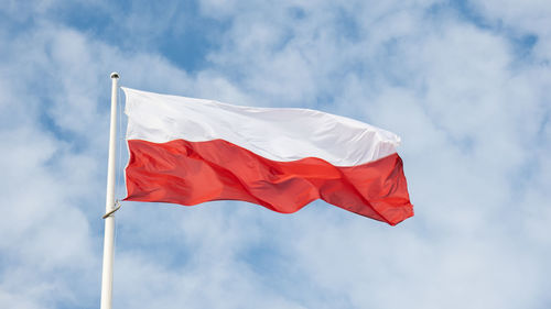 Flag of poland waving at wind against beautiful blue sky. polish flag white and red flutters on blue