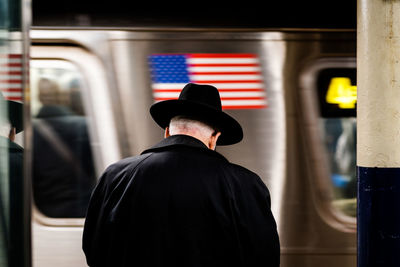 Rear view of man wearing hat against train at subway station