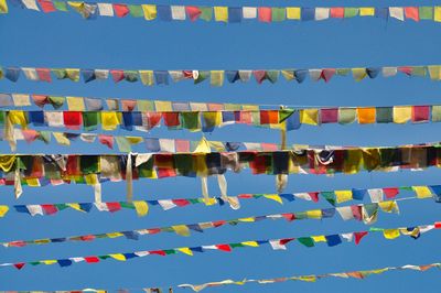 Low angle view of multi colored flags against blue sky