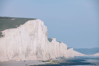 Rock formations by sea against clear sky