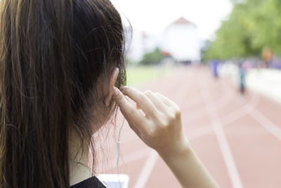 Close-up of athlete wearing headphones while standing running track