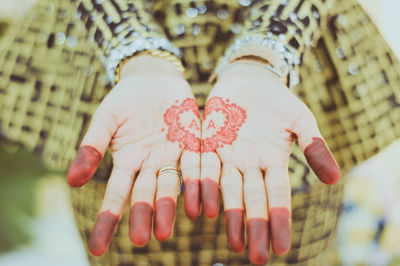 Midsection of woman with henna tattoo on hands