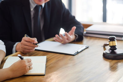 Midsection of man holding paper while sitting on table