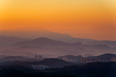 Scenic view of silhouette mountains against orange sky