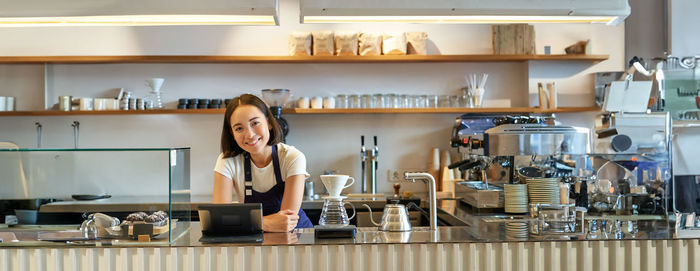 Portrait of young woman standing in kitchen