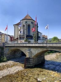 Bridge over river by building against sky