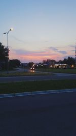 Illuminated street against sky at sunset