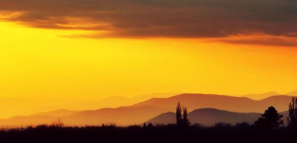 Scenic view of silhouette mountains against romantic sky at sunset