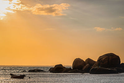 Rocks on sea against sky during sunset