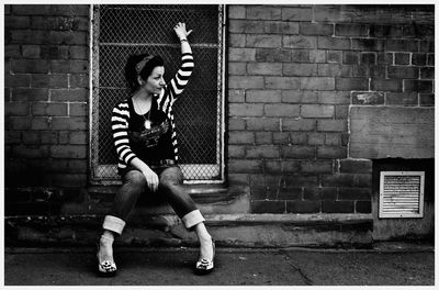 Full length of woman sitting on window sill