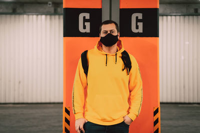 Portrait of young man standing against orange wall