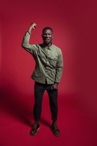 Full length portrait of man standing against red background