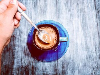 Cropped hand having coffee on wooden table