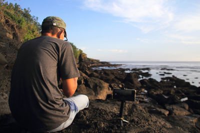 Rear view of man photographing sea against sky